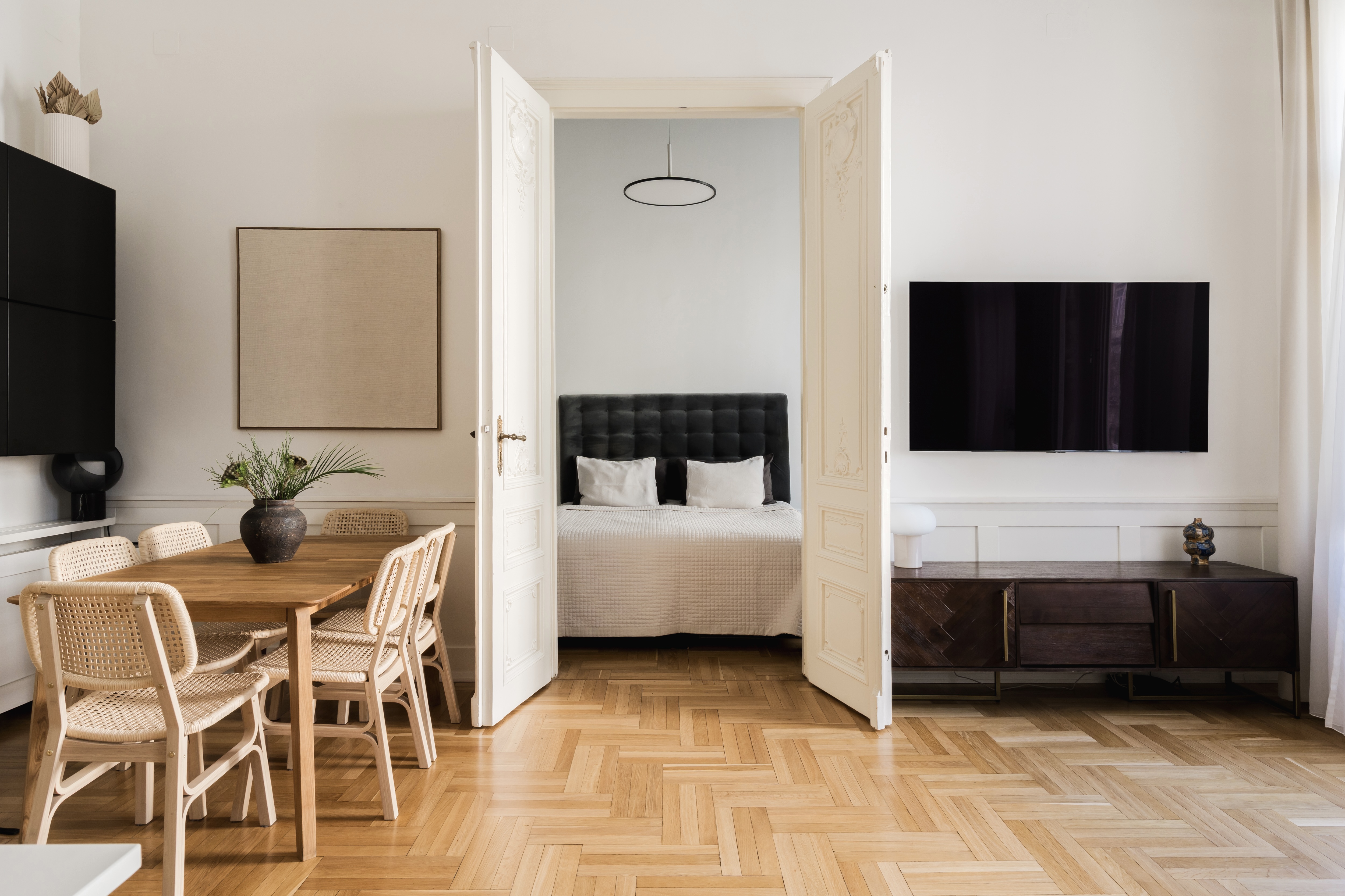 Elegant living and dining space with herringbone floors and classic double doors