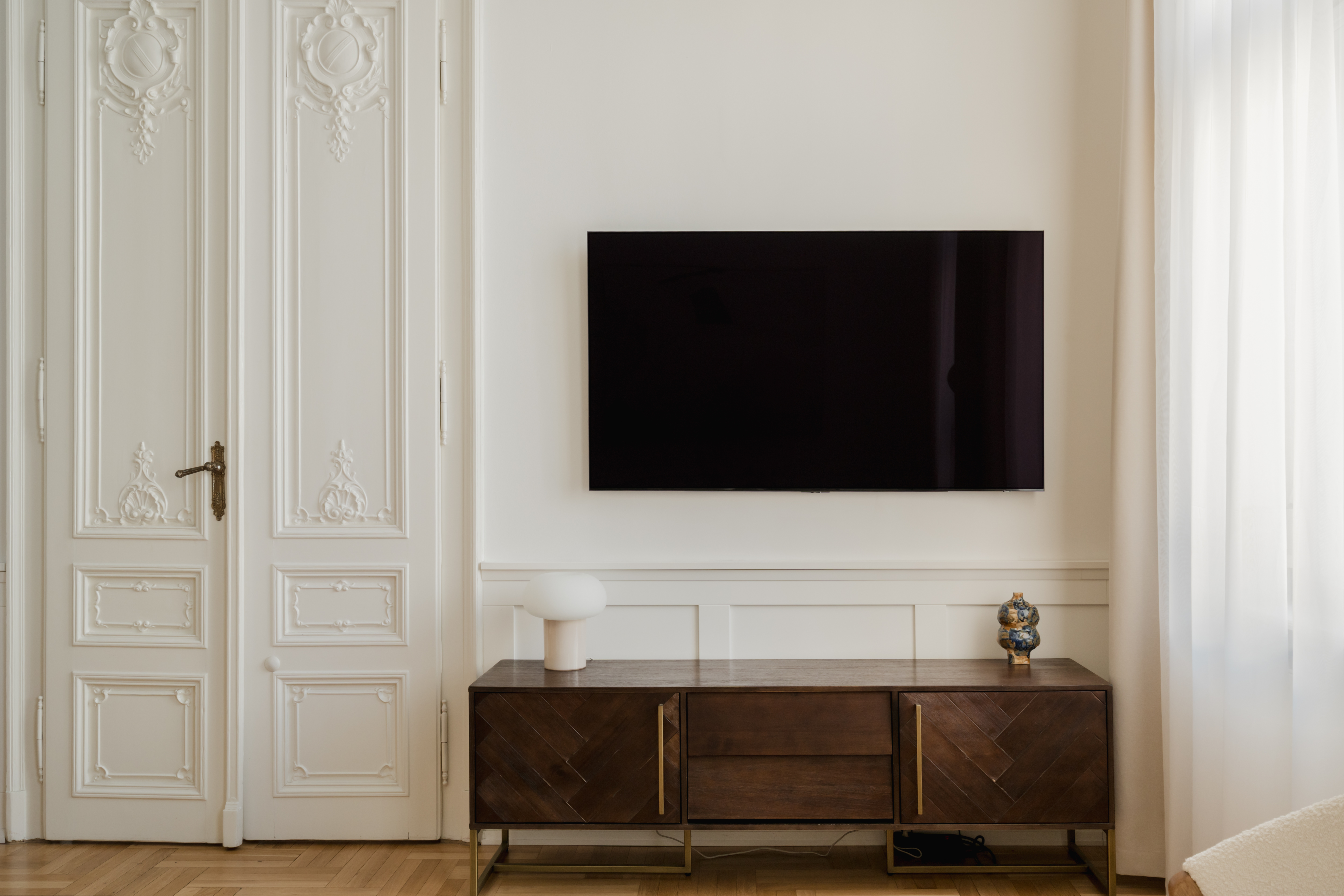 Living room with ornate period doors and walnut media console